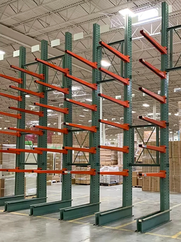 Empty green and orange Cantilever Racks are set up in a large warehouse, with palletized goods visible in the background.