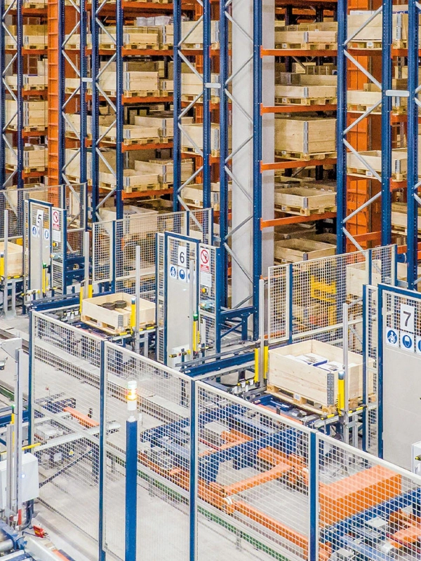 Automated warehouse with stacked shelves, pallets of goods, conveyor systems, Industrial Safety Guard Fencing, safety barriers, and numbered signage for organization.