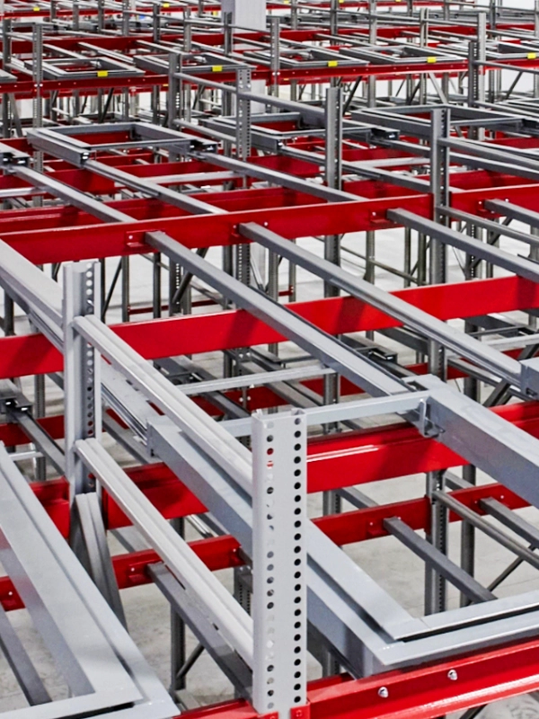Rows of empty industrial metal racks with red and gray beams in a warehouse, featuring Push-Back Rack systems for efficient storage and easy pallet access.