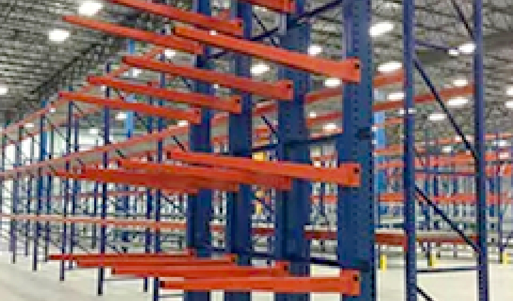 Rows of empty cantilever rack shelving with blue frames and orange beams, set inside a well-lit, spacious storage facility.