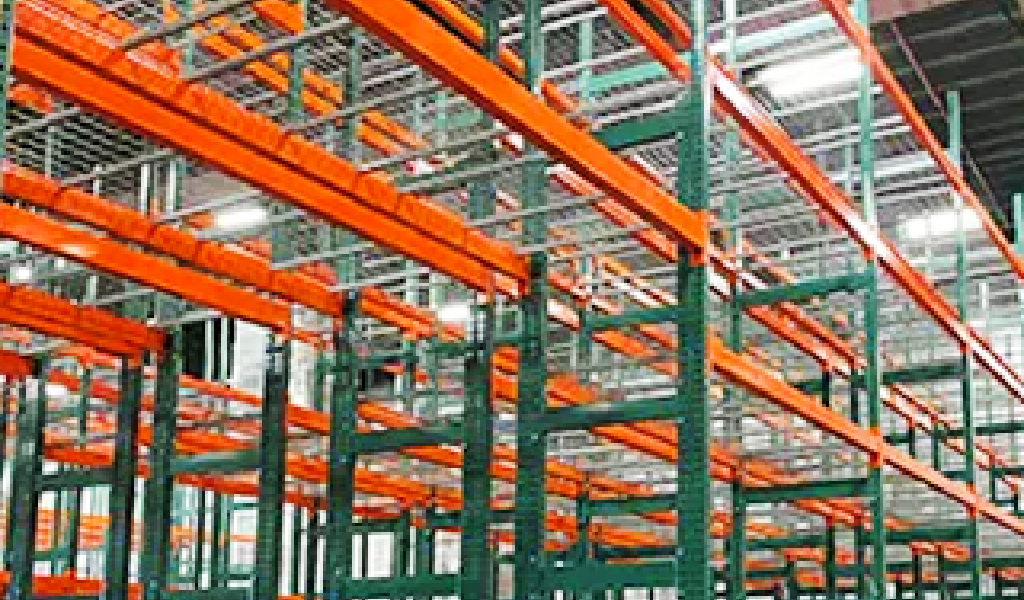 Empty industrial warehouse featuring a Double-Deep Rack racking system with orange beams and green metal frames, arranged in rows inside a large building.