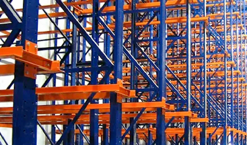 Rows of empty blue and orange metal Drive-In Rack shelving extend into the distance, creating a striking geometric pattern.