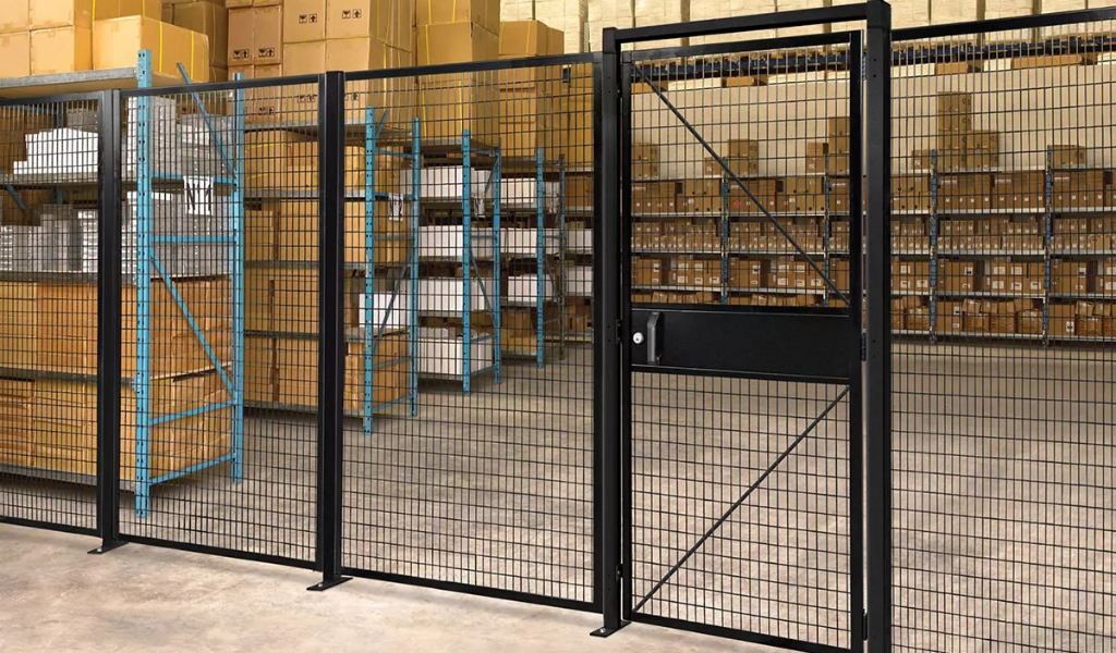 A locked Industrial Safety Guard Fencing with a gate separates a warehouse storage area filled with shelves and stacked cardboard boxes.