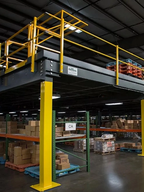 Warehouse interior featuring Steel Platforms & Mezzanines, yellow metal mezzanine, shelving stocked with boxes, and a sign labeled "CA" hanging above the aisle.
