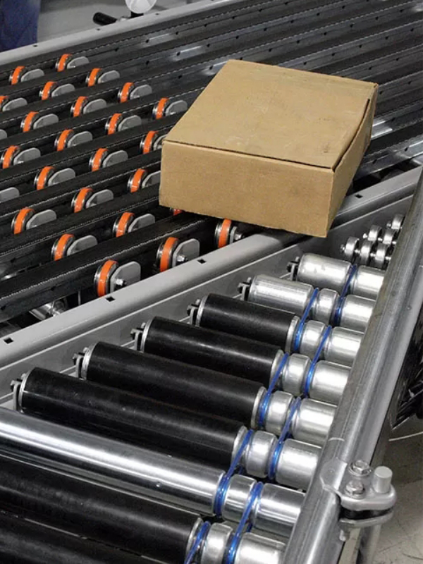 A closed cardboard box moves along a metal roller conveyor system, showcasing the efficiency of modern Conveyor Systems in an industrial setting.