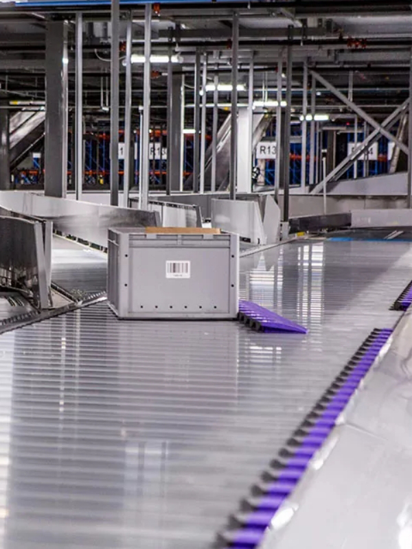 A gray box with a barcode moves along a conveyor belt, seamlessly integrated into advanced Conveyor Systems within an industrial sorting or distribution facility.