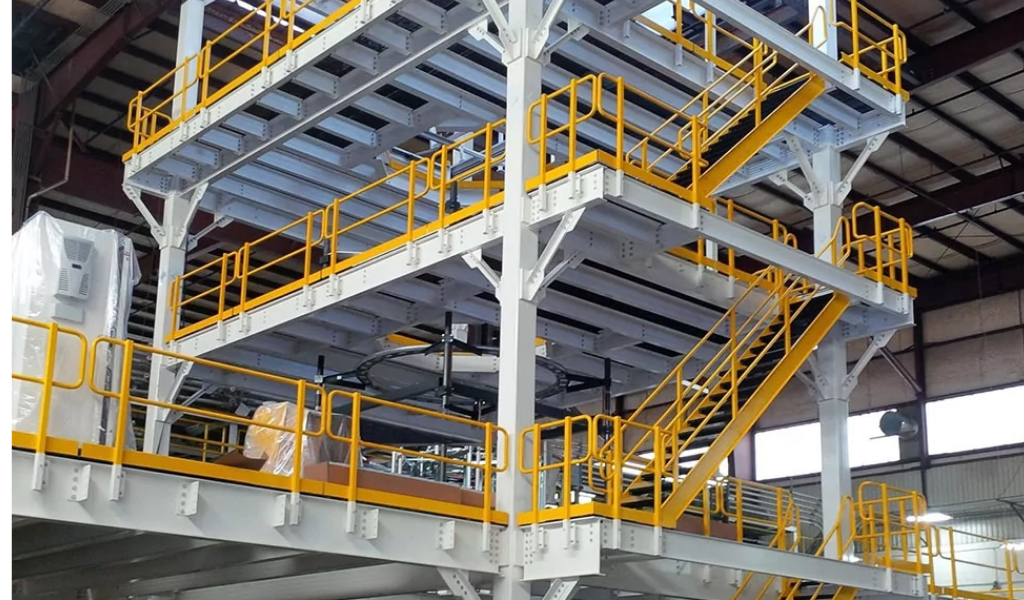 A multi-level industrial steel platform structure with yellow safety railings and stairs, showcasing the versatility of Steel Platforms & Mezzanines inside a warehouse.